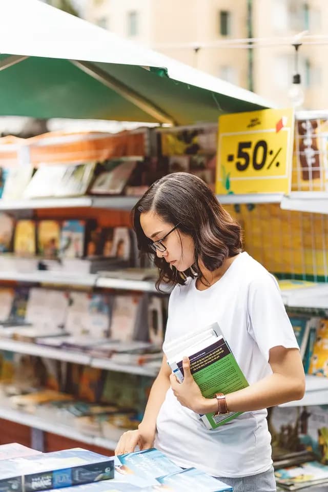 Student browsing books at an outdoor market stall