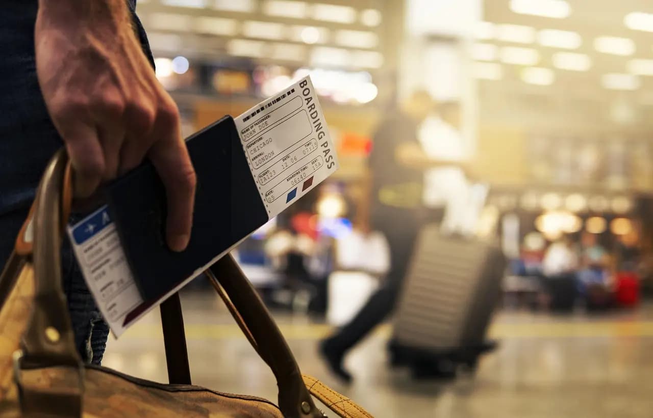 Boarding pass held at a sunlit airport